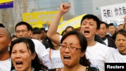 Family members of passengers on board Malaysia Airlines MH370 shout slogans during a protest in front of the Malaysian embassy in Beijing, March 25, 2014.