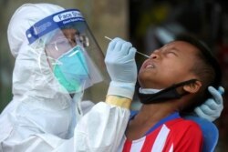 A medical worker performs a nose swab on a migrant boy at a seafood market, amid the coronavirus disease (COVID-19) outbreak, in Samut Sakhon province, in Thailand, December 19, 2020. REUTERS/Panumas Sa