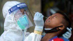 A medical worker performs a nose swab on a migrant boy at a seafood market, amid the coronavirus disease (COVID-19) outbreak, in Samut Sakhon province, in Thailand, December 19, 2020. REUTERS/Panumas Sa