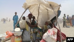 Femmes et enfants évacués des îles du lac Tchad assis sous une tente improvisée à N'Guigmi, Niger, le 5 mai 2015.
