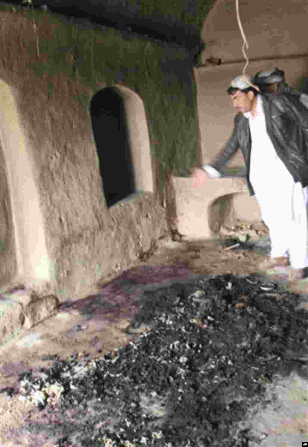 A man points to bloodstains, where witnesses say Afghans were killed by a U.S. service member, in Panjwai, Kandahar province south of Kabul, Afghanistan, Sunday, March 11, 2012. A U.S. service member walked out of a base in southern Afghanistan before daw