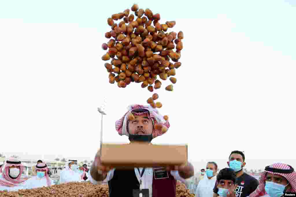 A farmer throws dates in the air during Unaizah Season for Dates, at Unaizah city in Al-Qassim province, Saudi Arabia.