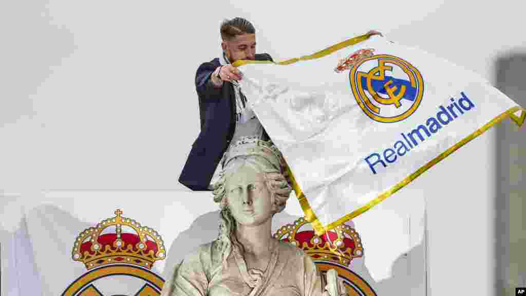 Le joueur du Real Madrid Sergio Ramos lie un drapeau de l'équipe autour du cou de la déesse Cibeles, lors du défilé dans les rues de Madrid, le 29 mai 2016.