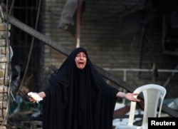A woman reacts at the site of a car bomb attack, at the entrance to the neighbourhood of Kadhimiya in Baghdad, October 15, 2014. REUTERS/Ahmed Saad