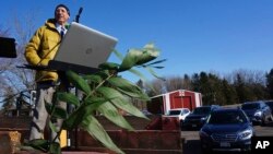 In this April 5, 2020 photo, Pastor John Hanson stands atop a truck as members of his congregation arrive for Sunday morning "drive-in worship" at Peace Lutheran Church in Baldwin, Wis. (AP Photo/Giovanna Dell'Orto)