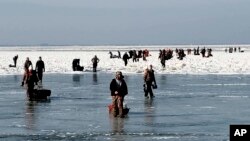 In this photo provided by the U.S. Coast Guard, ice fishermen walk to land after being stuck on an ice floe that broke free from land north of Catawba Island, March 9, 2019, in Ohio.