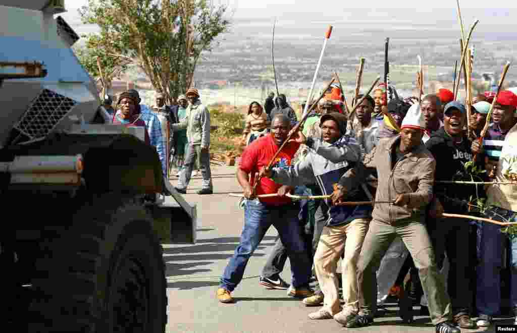 Striking miners react as they make way for a security vehicle at the AngloGold Ashanti mine in Carletonville, northwest of Johannesburg, South Africa, October 25, 2012.