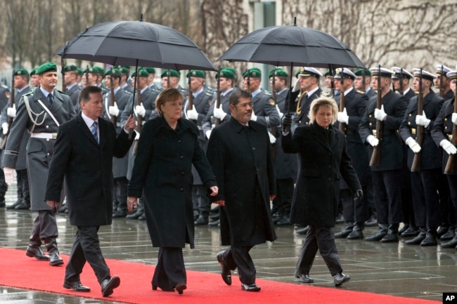 FILE - German Chancellor Angela Merkel, second left, welcomes the President of Egypt, Mohamed Morsi, second right, with military honors at the chancellery in Berlin, Germany, Wednesday, Jan. 30, 2013.