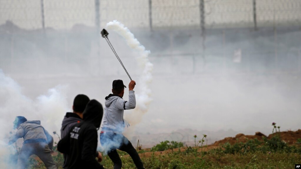 یکی از معترضان فلسطینی در حال پرتاب یک کپسول گاز اشک آور به آن طرف حصارهای مرزی بین غزه و اسرائیل - ۱۰ فروردین ۱۳۹۸ 