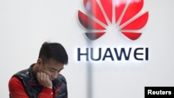 FILE - A staff member stands in front of a Huawei shop in Beijing, China, March 7, 2019. 