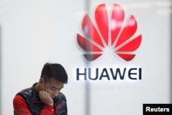 FILE - A staff member stands in front of a Huawei shop in Beijing, China, March 7, 2019.