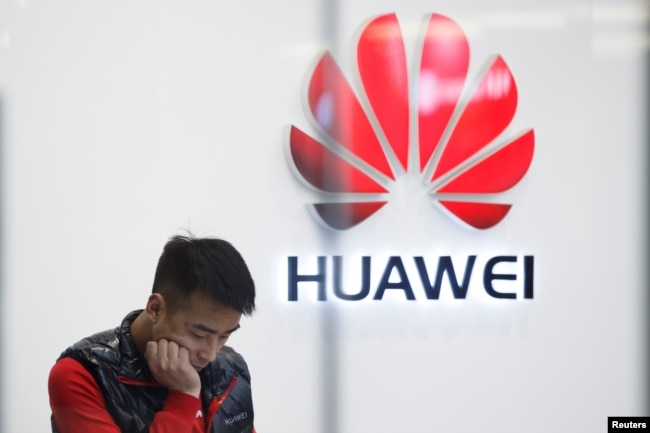 FILE - A staff member stands in front of a Huawei shop in Beijing, China, March 7, 2019.