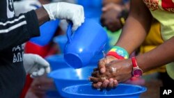 Une dame se lave les mains avec de l'eau et du savon contre le nouveau coronavirus lors d'une course de 5 km pour femmes dans la capitale Addis-Abeba, Ethiopie, dimanche 15 mars 2020. (AP Photo/Mulugeta Ayene)