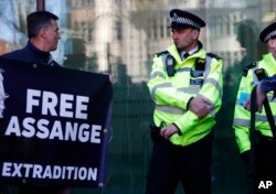 A protester looks across at police officers outside Westminster magistrates court where WikiLeaks founder Julian Assange was appearing in London, April 11, 2019.