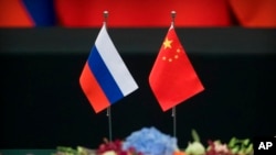 资料照：2018年6月8日，在北京人民大会堂举行的签字仪式前，桌子上的俄罗斯（左）和中国国旗。