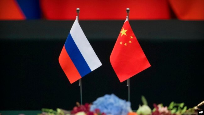 FILE - Russian, left, and Chinese flags sit on a table before a signing ceremony at the Great Hall of the People in Beijing, June 8, 2018.
