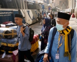 Beberapa jemaah umrah asal Indonesia menunggu bus yang akan membawa mereka meninggalkan kota Makkah, Arab Saudi, 5 Maret 2020.
