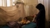 FILE - A woman changes the clothes of her baby in the malnourished ward of the Mohammed Khan Hospital in Sayedabad district, Wardak province, Afghanistan, Oct. 11, 2021.