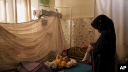 Seorang perempuan tampak mengganti baju bayinya yang tengah dirawat di Rumah Sakit Mohammed Khan di distrik Sayedabad, provinsi Wardak, Afghanistan, pada 11 Oktober 2021. (Foto: AP/Felipe Dana)
