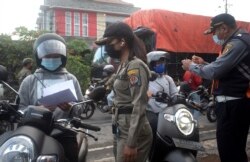 Para petugas Satpol PP memeriksa para pengendara motor di sebuah pos pemeriksaan di tehang penerapan PPKM darurat untuk meredam pandemi virus COVID-19 di Denpasar, Bali, 8 Juli 2021. (Foto: Firdia Lisnawati/AP)