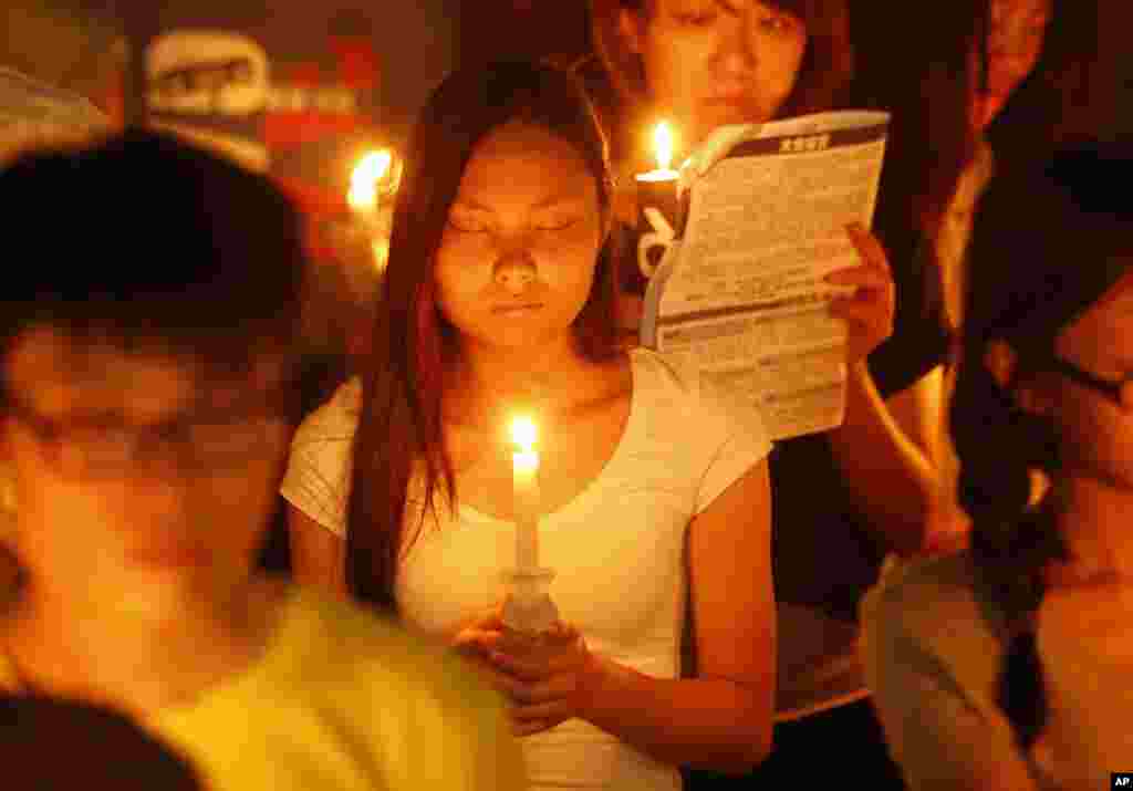 A woman closes her eyes as she joins tens of thousands of people attending a candlelight vigil at Victoria Park in Hong Kong to mark the 25th anniversary of crackdown in Tiananmen Square, June 4, 2014. 