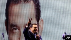Television comedian and presidential candidate for the National Front of Convergence party Jimmy Morales, flashes a victory sign to his supporters at his party headquarters in Guatemala City, Sunday, Sept. 6, 2015.