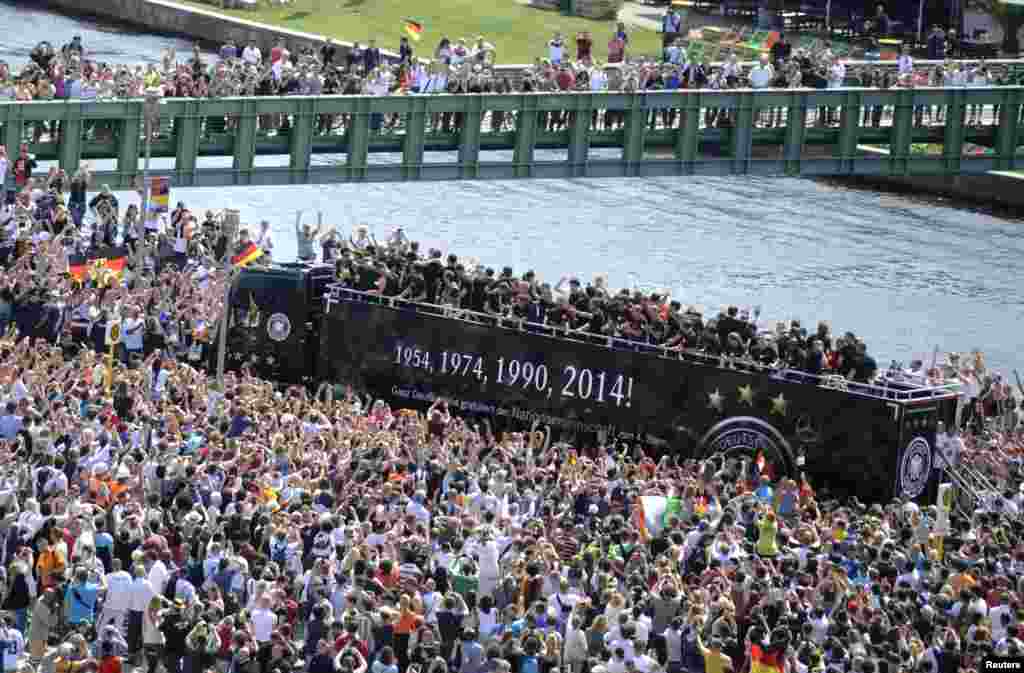 Fans throng a street along the river Spree in central Berlin to cheer Germany&#39;s 2014 Brazil World Cup squad as they proceed in an open-top bus through the capital during a parade to mark the team&#39;s victory.