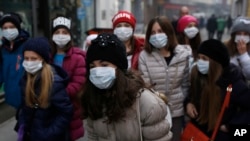 A group of school children walk on street with face mask in Sarajevo, Bosnia, on Wednesday, Dec. 23, 2015.