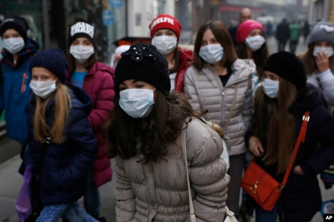 A group of school children walk on street with face mask in Sarajevo, Bosnia, on Wednesday, Dec. 23, 2015.