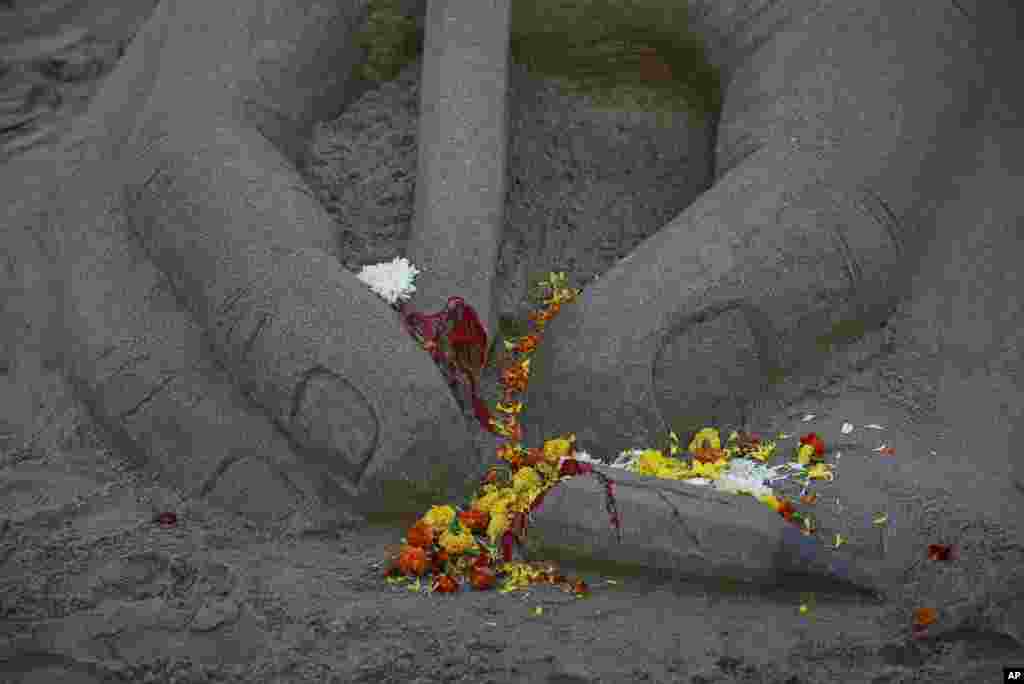 Flowers are seen scattered on a broken pencil sand sculpture made by an artist in tribute to the victims of the shooting by gunmen at the offices of French satirical weekly Charlie Hebdo, at a beach in Mumbai, India.