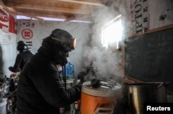 FILE - A woman makes coffee in a kitchen in the Oceti Sakowin camp as "water protectors" continue to demonstrate against plans to pass the Dakota Access pipeline near the Standing Rock Sioux Reservation, near Cannon Ball, N.D., Dec. 6, 2016.
