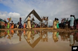 Rohingya refugees are reflected in a puddle during Eid al Adha celebration at Kutupalong refugee camp, Bangladesh, Wednesday, Aug. 22, 2018.