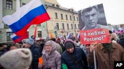 FILE - People march in memory of opposition leader Boris Nemtsov, portrait at right, in Moscow, Russia, Feb. 26, 2017. 