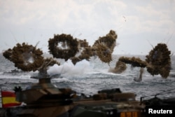 FILE - Amphibious assault vehicles of the South Korean Marine Corps fire smoke bombs as they move to land on the shore during a U.S.-South Korea joint landing operation drill as a part of the two countries' annual military training.