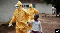 Des travailleurs de la santé s'occupant d'un enfant présentant des symptômes d'Ebol au Libéria (AP Photo/Jerome Delay, File)