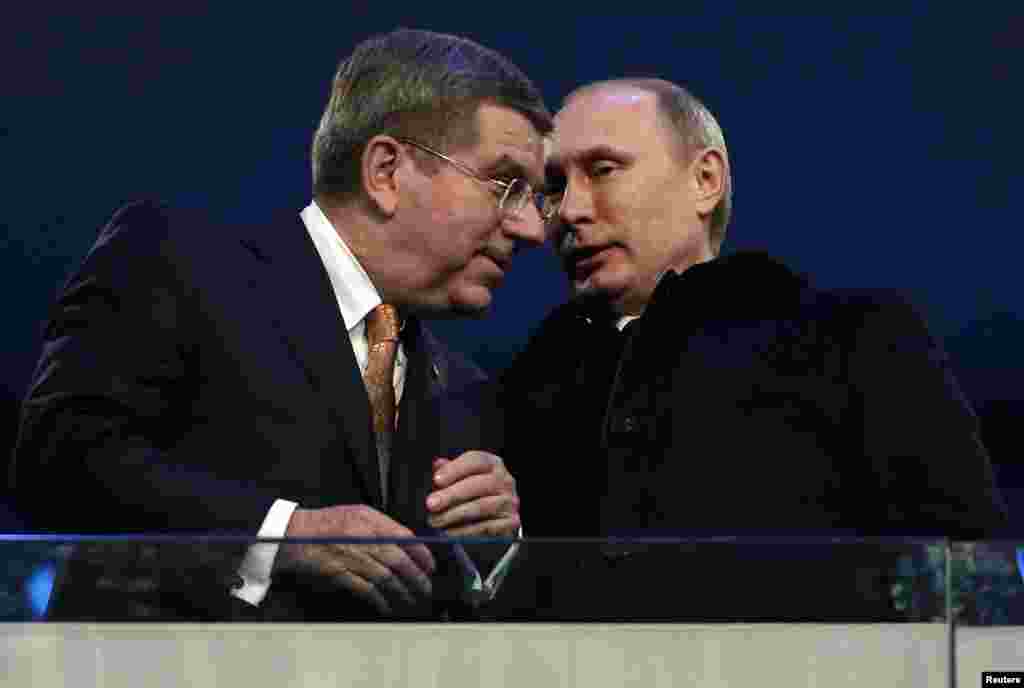 International Olympic Committee President Thomas Bach of Germany talks to Russian President Vladimir Putin during the opening ceremony of the 2014 Sochi Winter Olympics, Feb. 7, 2014. 