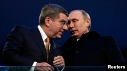International Olympic Committee President Thomas Bach of Germany talks to Russian President Vladimir Putin during the opening ceremony of the 2014 Sochi Winter Olympics, Feb. 7, 2014.
