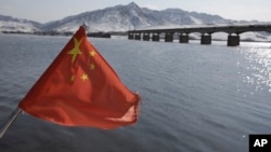A Chinese flag is hoisted near the Hekou Bridge, right, linking China and North Korea, which was bombed in the 1950's during the Korean War, in Hekou, China, February 7, 2013.