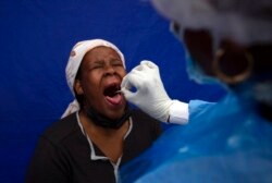FILE - A throat swab is taken from a patient to test for COVID-19 at a facility in Soweto, South Africa, Dec. 2, 2021.