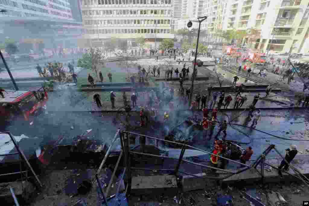 Bombeiros libaneses apagam os veículos que ardiam no local da explosão em Beirute, Líbano, Dez. 27, 2013. 