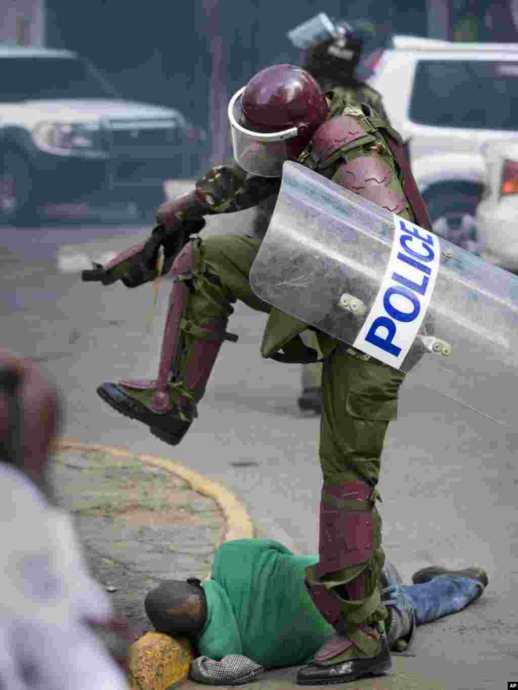 A Kenyan riot policeman repeatedly kicks a protester who tripped during a protest in downtown Nairobi. Police tear-gassed and beat opposition supporters during a demonstration to demand the disbandment of the electoral authority over alleged bias and corruption.