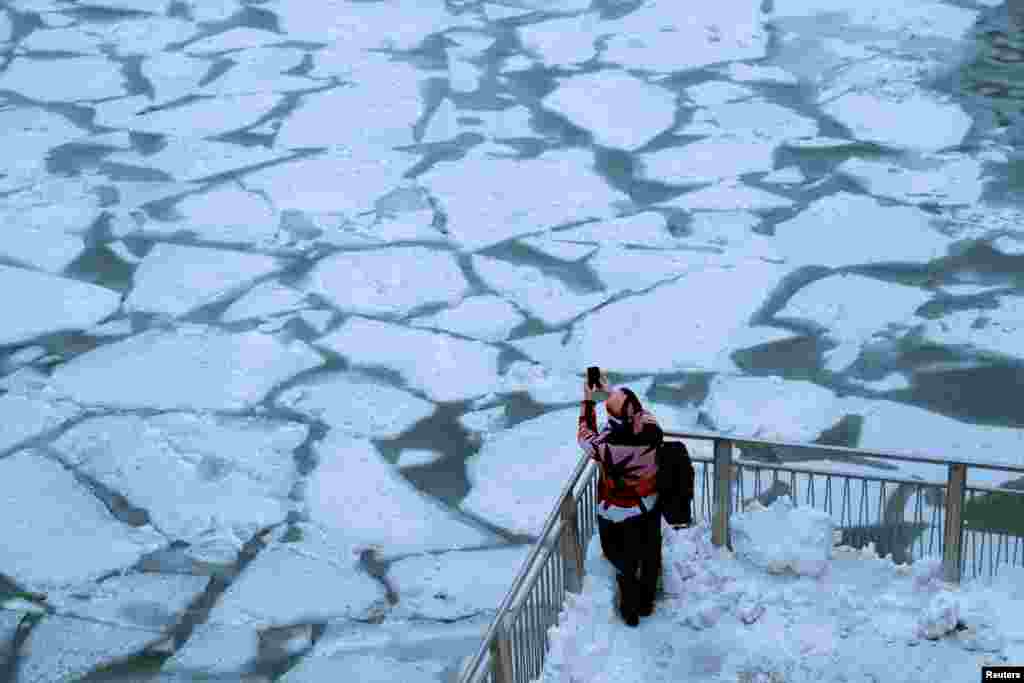 A pedestrian takes a photo of the frozen Chicago River as a bitter cold phenomenon called the "polar vortex" descends on much of the central and eastern United States, in Chicago, Illinois, Jan. 29, 2019.