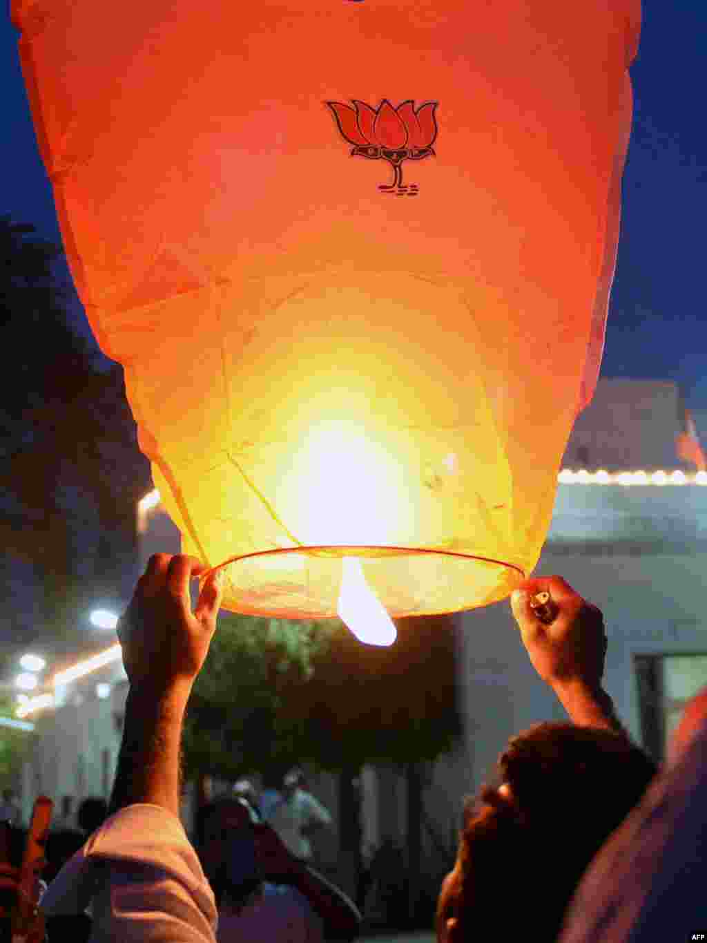 An Indian Bharatiya Janata Party (BJP) supporter prepares to launch a hot air lantern adorned with the BJP lotus party symbol at the party headquarters in New Delhi.