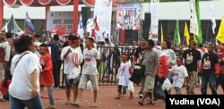 Sekelompok anak memakai atribut pasangan capres cawapres nomor urut 01 di tengah lokasi kampanye terbuka capres 01, Joko Widodo, di Solo, Selasa, 9 April 2019. (Foto: VOA/Yudha)