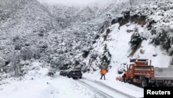 Kru Caltrans di Angeles National Forest, California, mencoba membantu mobil-mobil yang terhambat akibat hujan salju di Angeles Crest Highway, 28 November 2019.