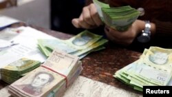 FILE - A cashier counts bolivars at a money exchange in Caracas, Venezuela, Feb. 24, 2015. 