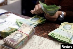 FILE - A cashier counts bolivars at a money exchange in Caracas, Venezuela, Feb. 24, 2015.