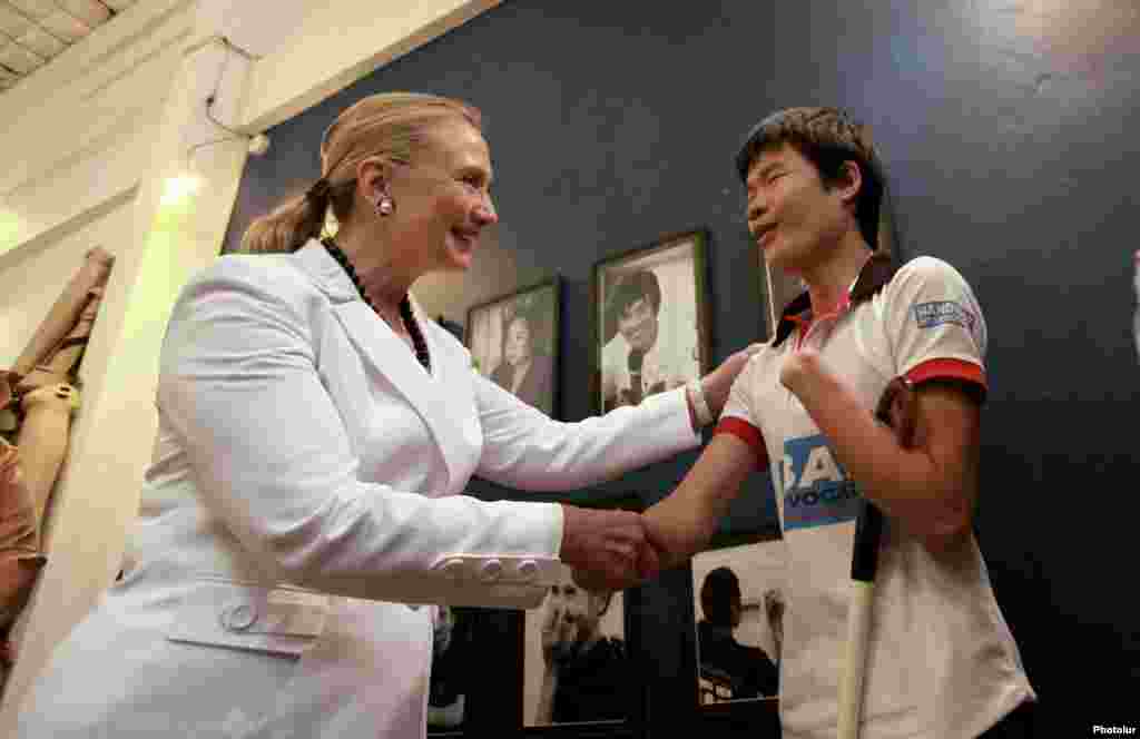 U.S. Secretary of State Hillary Clinton (L) talks to a disabled boy at the Cooperative Orthotic and Prosthetic Enterprise (COPE) visitor center in Vientiane July 11, 2012. COPE is a non-profit organisation that provides access to orthotic and prosthetic d