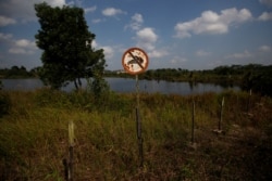 Tanda 'Dilarang Berenang" tampak di bekas lubang tambang batu bara yang terisi air di Kabupaten Kutai Kertanegara, Kalimantan Timur, 30 Agustus 2019. (Foto: Reuters)