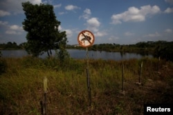 Tanda 'Dilarang Berenang" tampak di bekas lubang tambang batu bara yang terisi air di Kabupaten Kutai Kertanegara, Kalimantan Timur, 30 Agustus 2019. (Foto: Reuters)